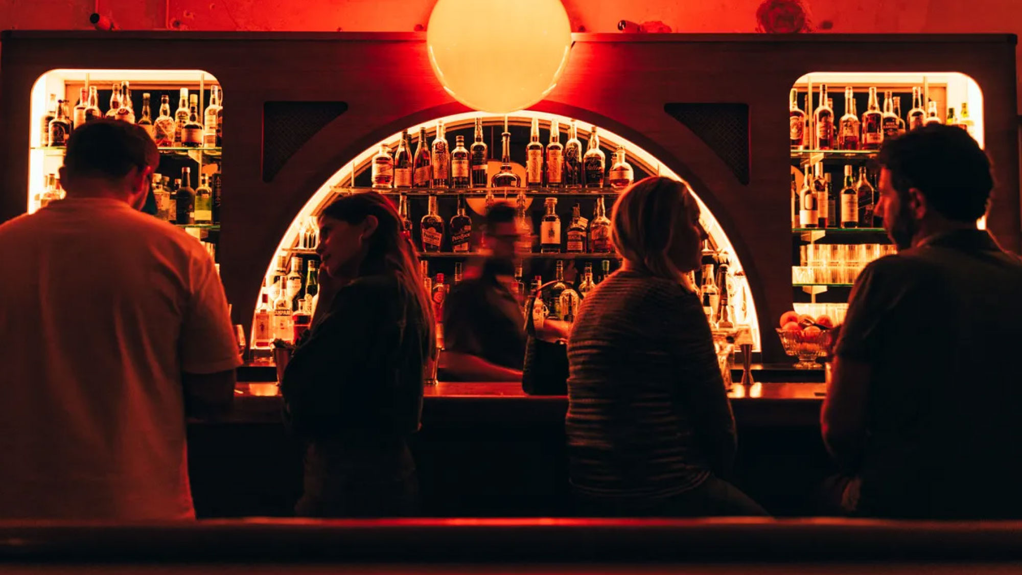 People enjoying a glowing red eclectic cocktail bar and nightlife