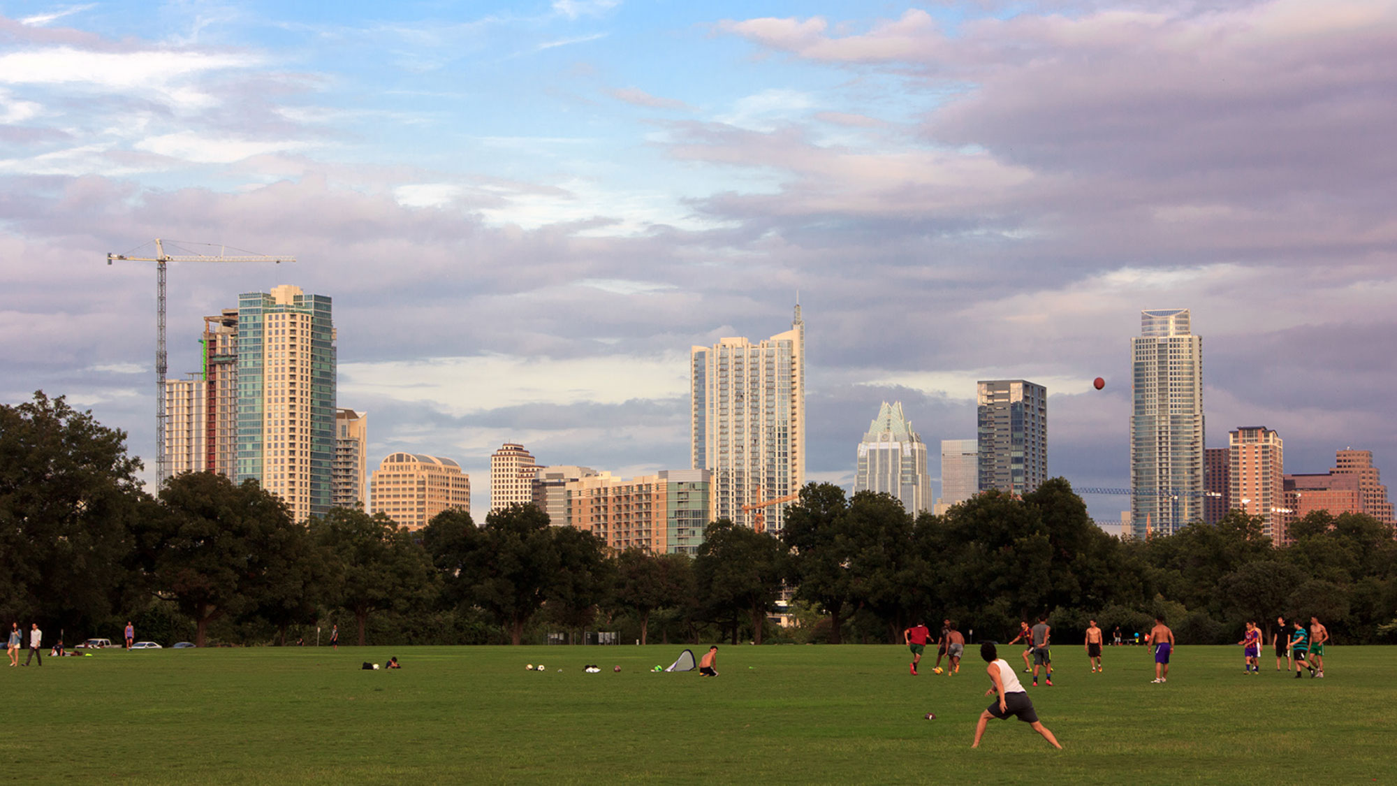 People playing in a green outdoor city park at dusk
